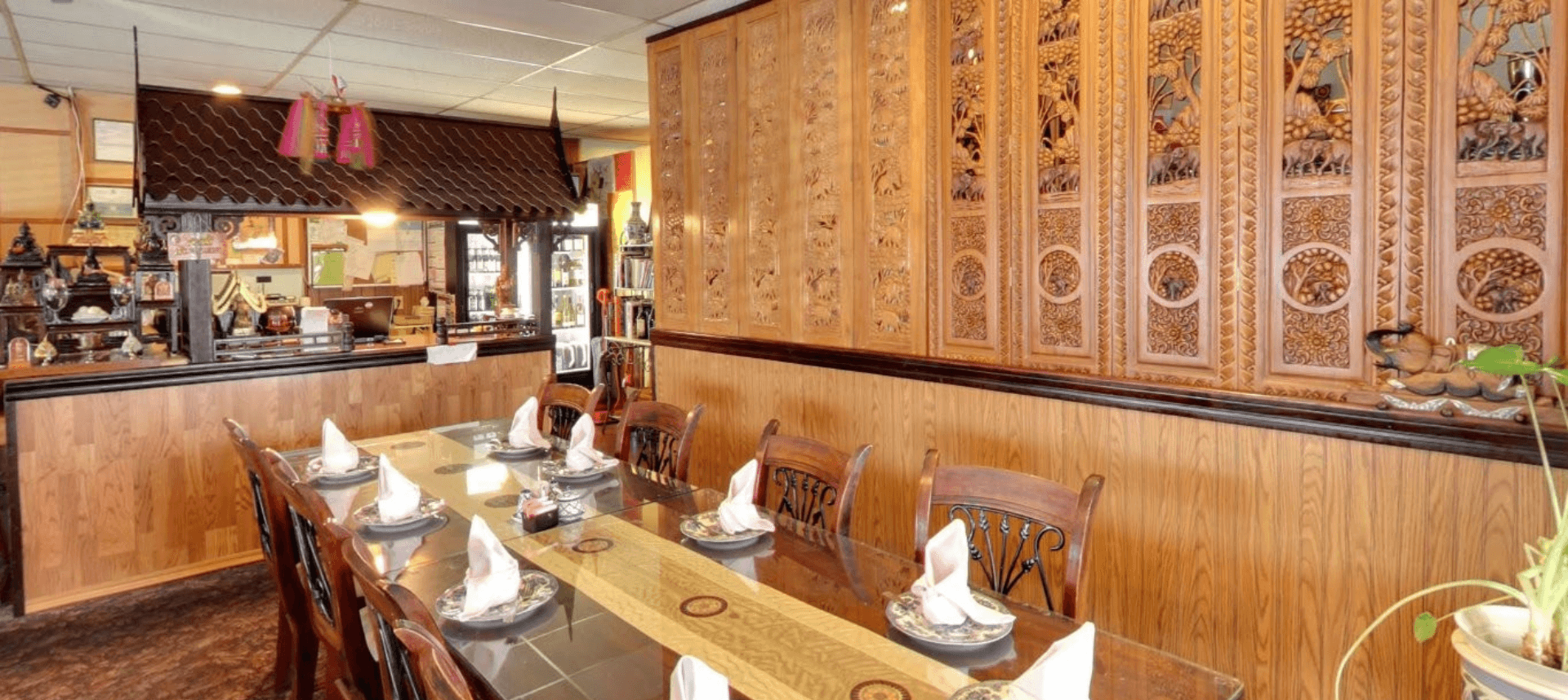 Interior dining room at Siam Thai Cuisine with carved wooden walls and a long communal table